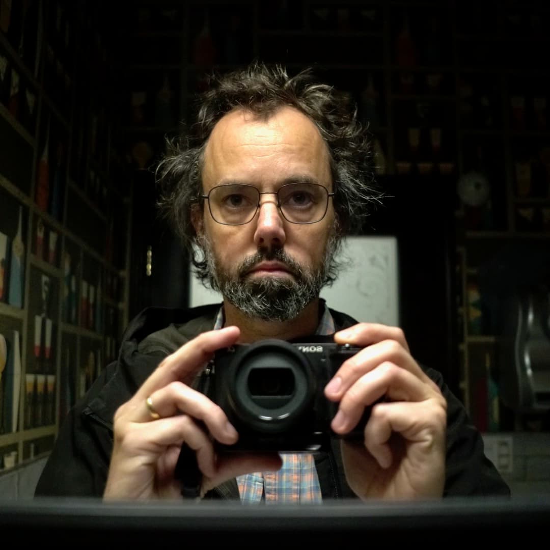 Self portrait of Bartram Nason in a mirror. He is wearing a black windbreaker and is holding a camera.